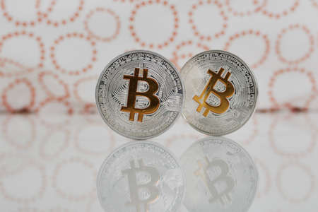 Digital currency physical silver yellow bitcoins on the white table near orange circles.の写真素材
