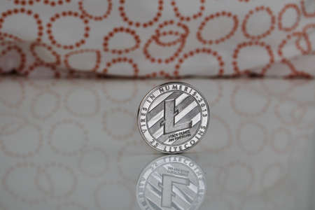 Digital currency physical silver Litecoin coin on the white table near orange circles.の写真素材
