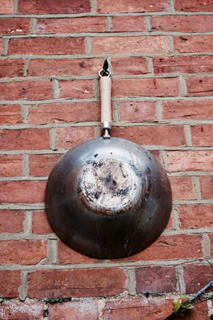Big old and dirty pan on the brick wall in the garden. Abstract concept.の写真素材