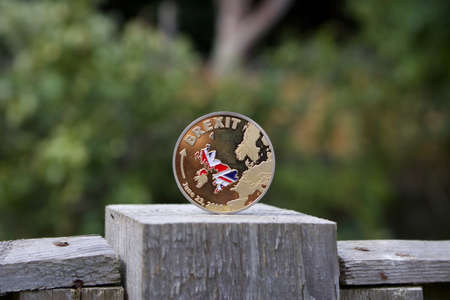 Gold brexit coin with british map on the wooden fence in the garden.のeditorial素材