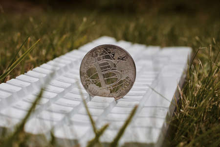 Digital currency physical silver bitcoin coin on white keyboard in green grass.の写真素材