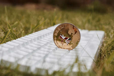 Europe leaving. Gold brexit coin with british map on the white keyboard in grass.の写真素材