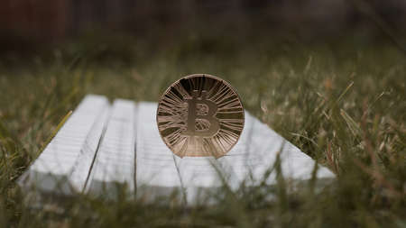 Digital currency physical gold bitcoin coin on white keyboard in green grass.の写真素材