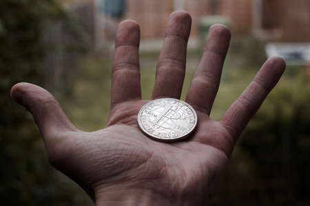 Cryptocurrency physical silver bitcoin coin on man hand outdoor.の写真素材