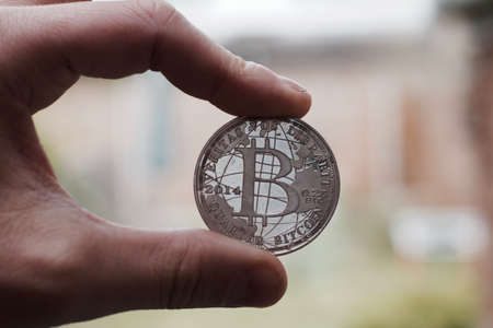 Cryptocurrency physical silver bitcoin coin holding in man fingers.の写真素材