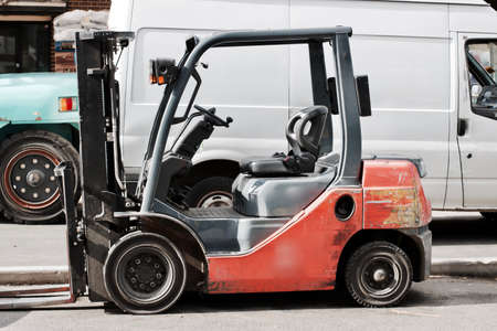 Old red outdoor lift truck near white big van and blue reach truck.の写真素材