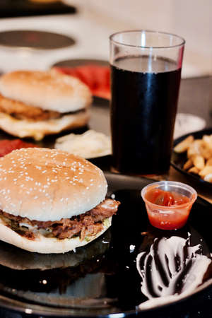 Tasty and fresh chicken burgers on black plate near coke in the kitchen.の写真素材