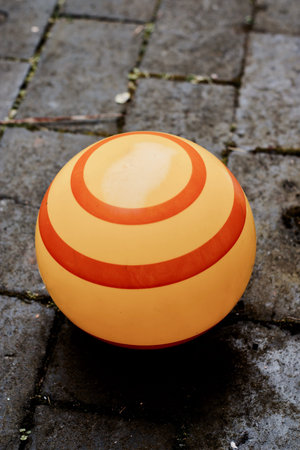 Big yellow ball with red stipes around on the stone floor in garden.の写真素材