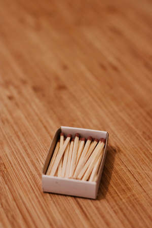 Small wooden matches in a box on the wooden board. Closeup photography.の写真素材