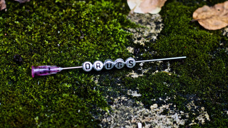 Silver inscription on the needle in green grass. Drugs on the needle.