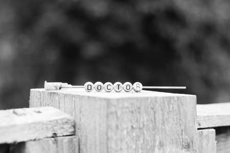 Silver letters on the needle. Doctor inscription on the wooden stick.の写真素材