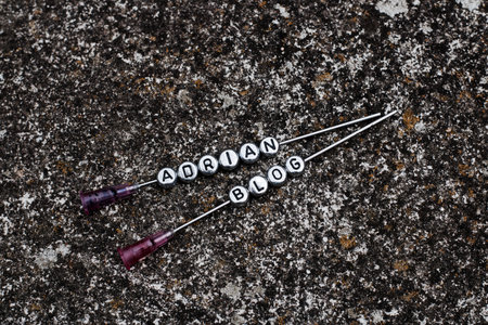 Small silver inscription Adrian blog on the needle in dark dirty background.の写真素材