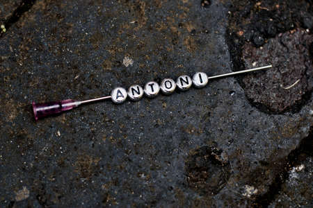 Small silver pins inscription antoni on the dirty background outdoor. Needle concept.の写真素材