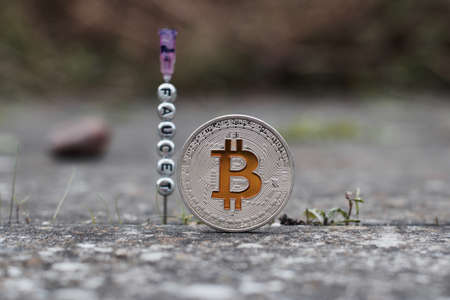 Digital currency physical silver bitcoin coin near faucet inscription on the needle.の写真素材