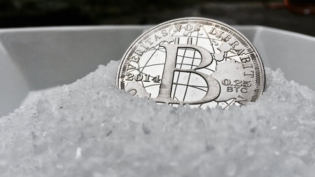 Digital currency physical metal coin on the white cristal background. Virtual cash concept.
