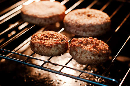 Hot tasty fish burgers on grate in hot oven in kitchen. Fast food kitchen concept.の写真素材