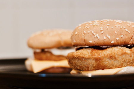Two tasty and fresh fish burgers on black plate in kitchen. Fast food concept.の写真素材
