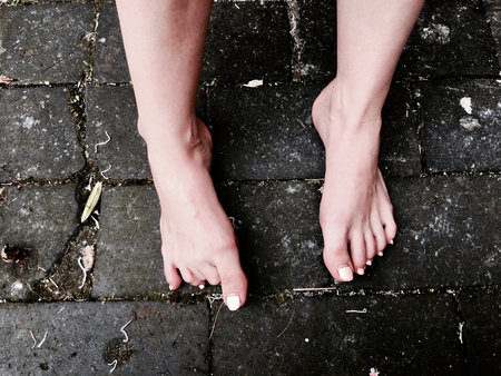 Naked white woman legs on the floor outdoor. Dirty background.の写真素材