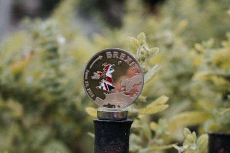 Europe leaving. Gold brexit coin with british map in green natural background.