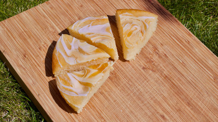 Tasty and fresh slices of lemon cake. Wooden board green outdoor cake concept.