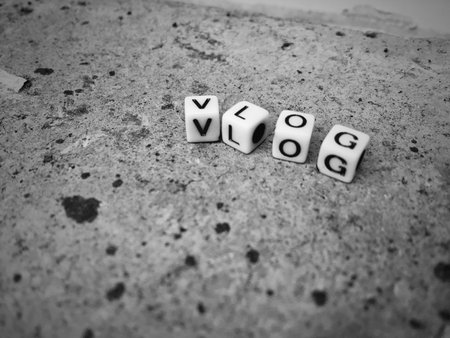 Vlog. White inscription. Small white square letters sign on the brown brick.