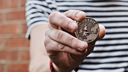 Europe leaving. Silver brexit coin in man hand. Coin with british map. Exit.の写真素材