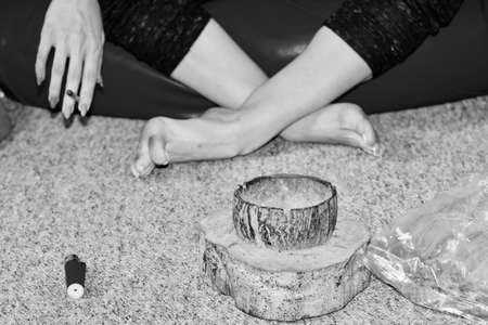 Addict young girl smoking weed on the pouf in living room. Marijuana in a bag.の写真素材