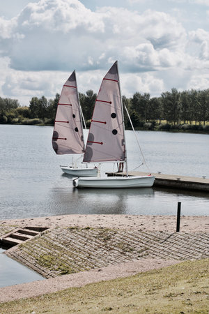 Two beautiful sailboats on the lake in Milton Keynes near pier. Bedfordshire.
