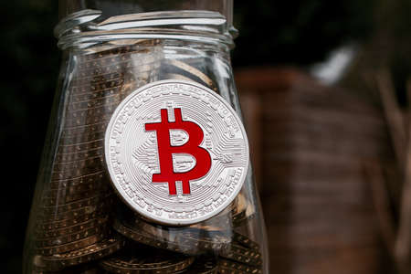 Digital currency physical silver bitcoin coin on glass jar with money.の写真素材