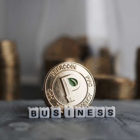 Digital currency physical gold peercoin coin near business white inscription.の写真素材