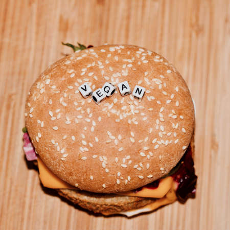 Delicious vegetarian burger in fresh roll with sezam on the wooden board in the kitchenの写真素材