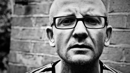 Young white man in dirty glasses staing on the wall. Black and white concept.の写真素材