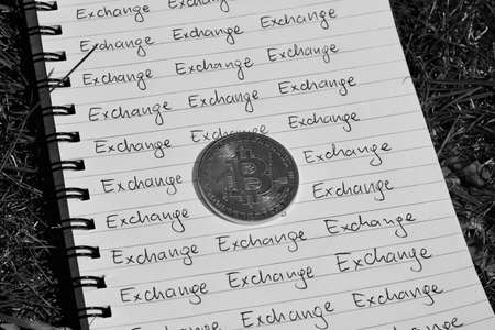 Digital currency physical metal bitcoin coin on the notebook with exchange inscription. Money outdoor concept.の写真素材