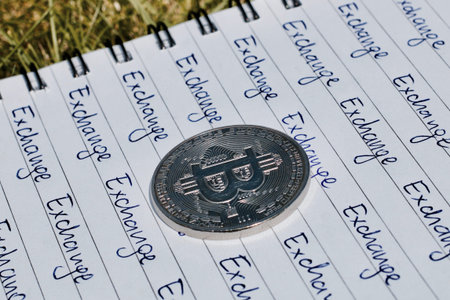 Digital currency physical metal bitcoin coin on the notebook with exchange inscription. Money...