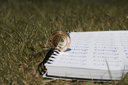 Digital currency physical gold peercoin coin on the exchange inscription. Outdoor green concept.の写真素材