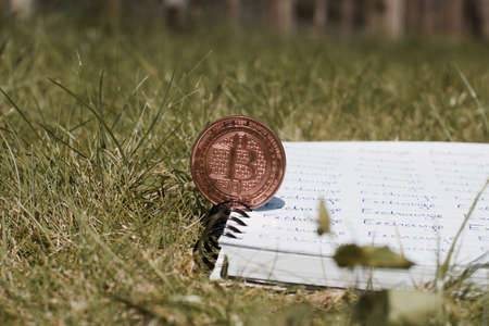 Digital currency physical metal bitcoin coin on the notebook with exchange inscription. Money outdoor concept.の写真素材