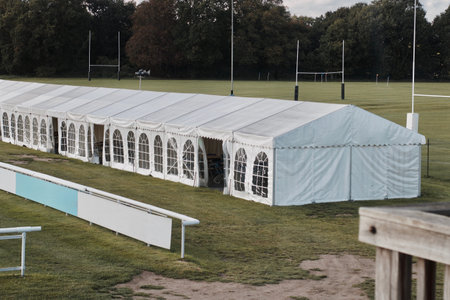 Big white banquet tent with windows near the green fields and tree.の写真素材