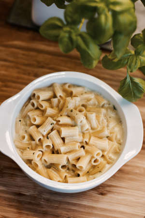 Delicious and fresh pasta on white plate on wooden board in the kitchen. Cooking concept.の写真素材