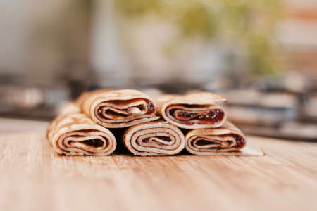 Delicious and fresh pancakes with strawberry sauce on the wooden board in the kitchen.の写真素材