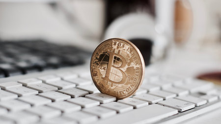 Digital currency physical metal bitcoin coin on the white keyboard near glass ball.の写真素材