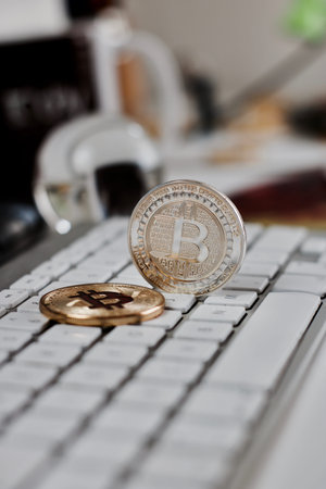 Digital currency physical metal bitcoin coin on the white keyboard near glass ball.