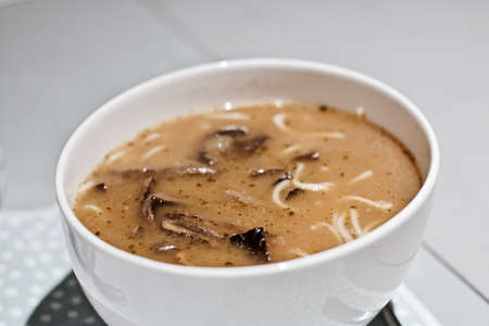 Fresh and delicious mushroom soup in the kitchen. Brown soup in a white plate.の写真素材