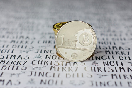 Digital currency physical metal bitcoin coin in christmas concept. White and grey background.