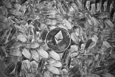 Digital currency physical metal ethereum coin. Yellow transparent drugs cryptocurrency concept.の写真素材
