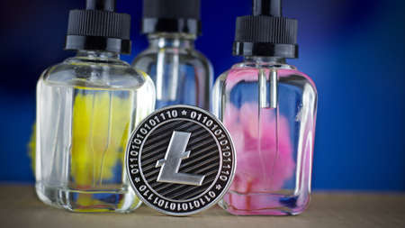 Digital currency physical metal litecoin coin. Yellow and pink serum bottles. Cryptocurrency concept.の写真素材