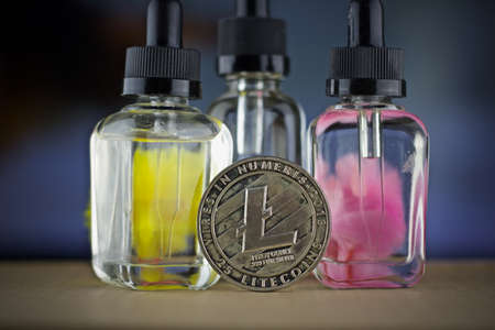 Digital currency physical metal litecoin coin. Yellow and pink serum bottles. Cryptocurrency concept.の写真素材