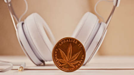 White headphones and brass marijuana metal coin. Cannabis concept.の写真素材