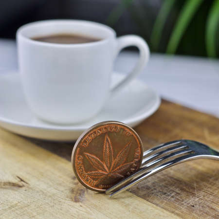 Metal brass marijuana coin near coffee. Drink cannabis concept.の写真素材