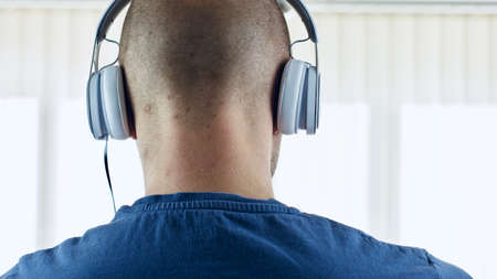 Young bald men in white headphones. Music concept.の写真素材