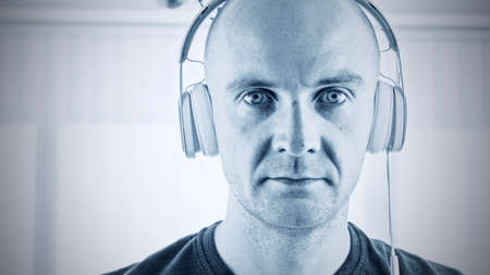 Young bald men in white headphones. Music concept.の写真素材